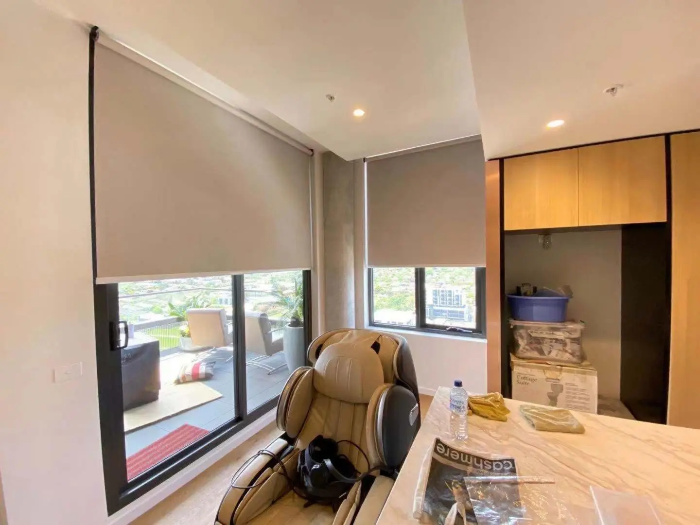 Modern apartment interior featuring light-colored roller blinds and a relaxing massage chair.