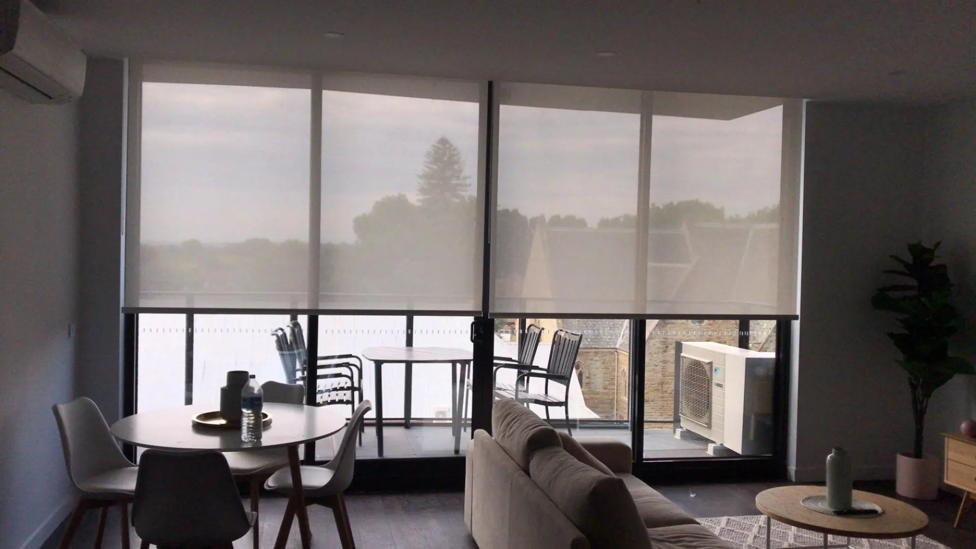 An apartment living room featuring large windows equipped with modern roller blinds.