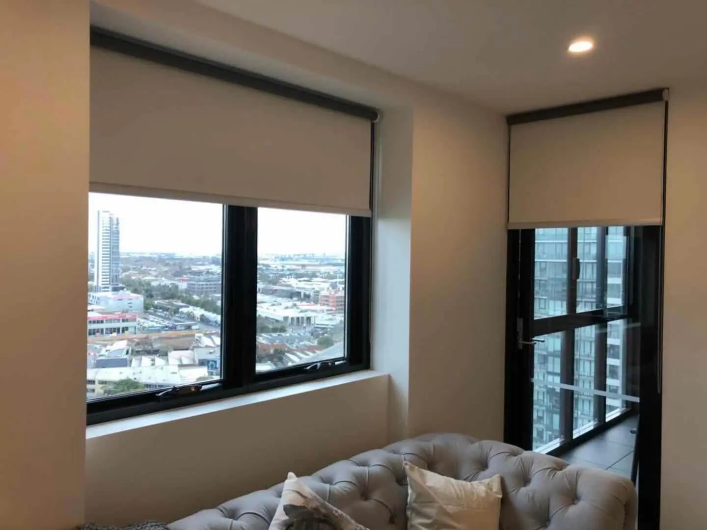 Stylish apartment windows feature roller blinds, offering city views and light control.