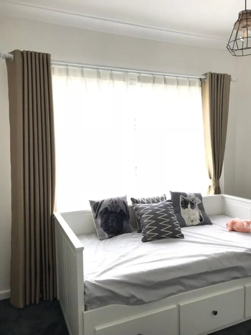 Daybed with animal pillows and neutral curtains.