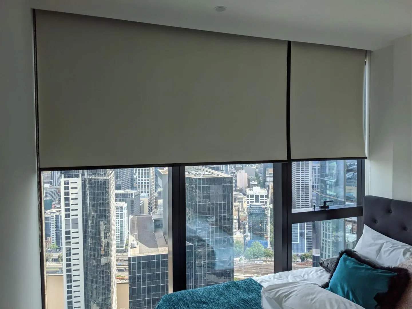 City views from a bedroom with roller shades.