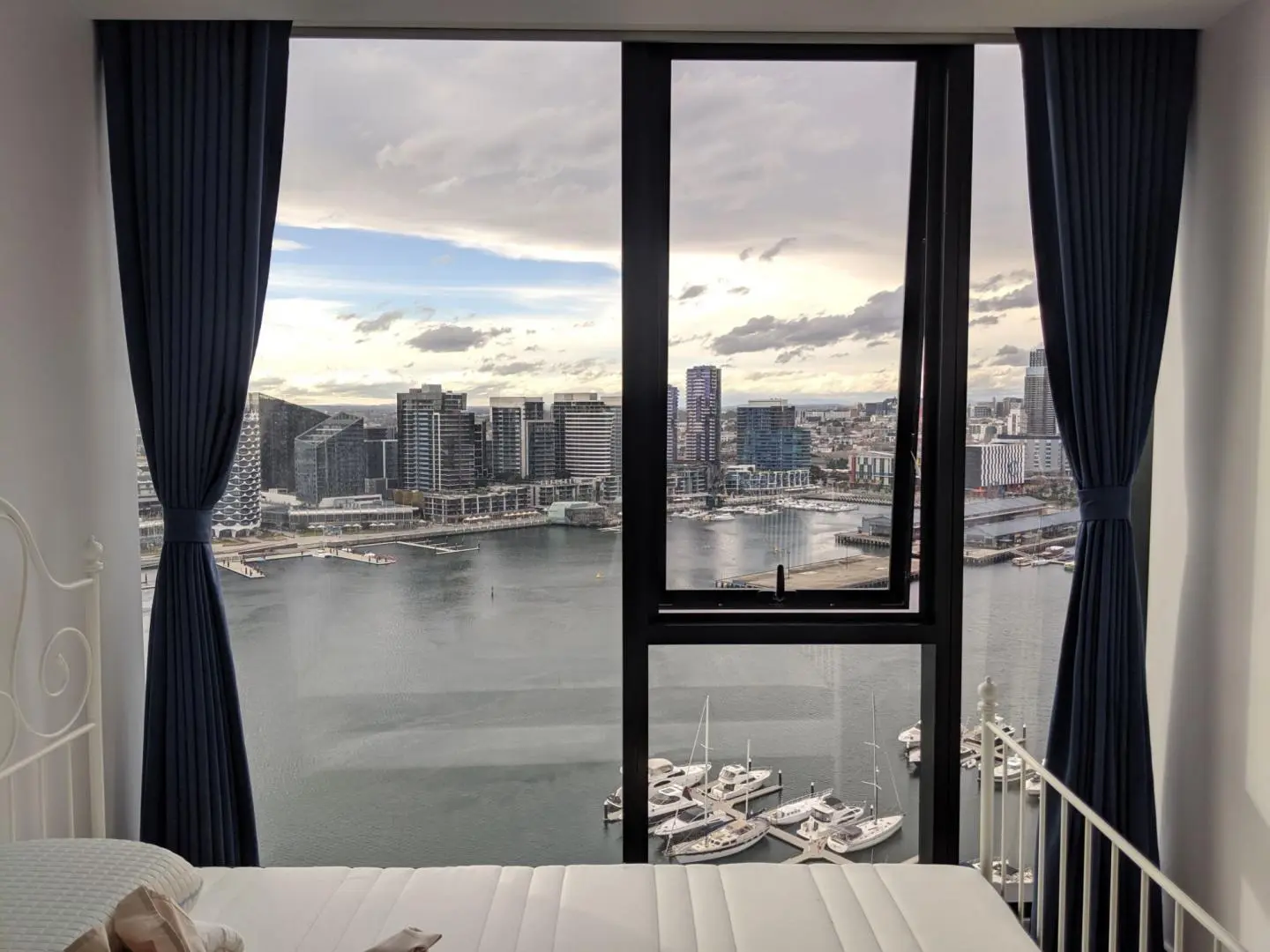 City view from a cozy bedroom with blue curtains.
