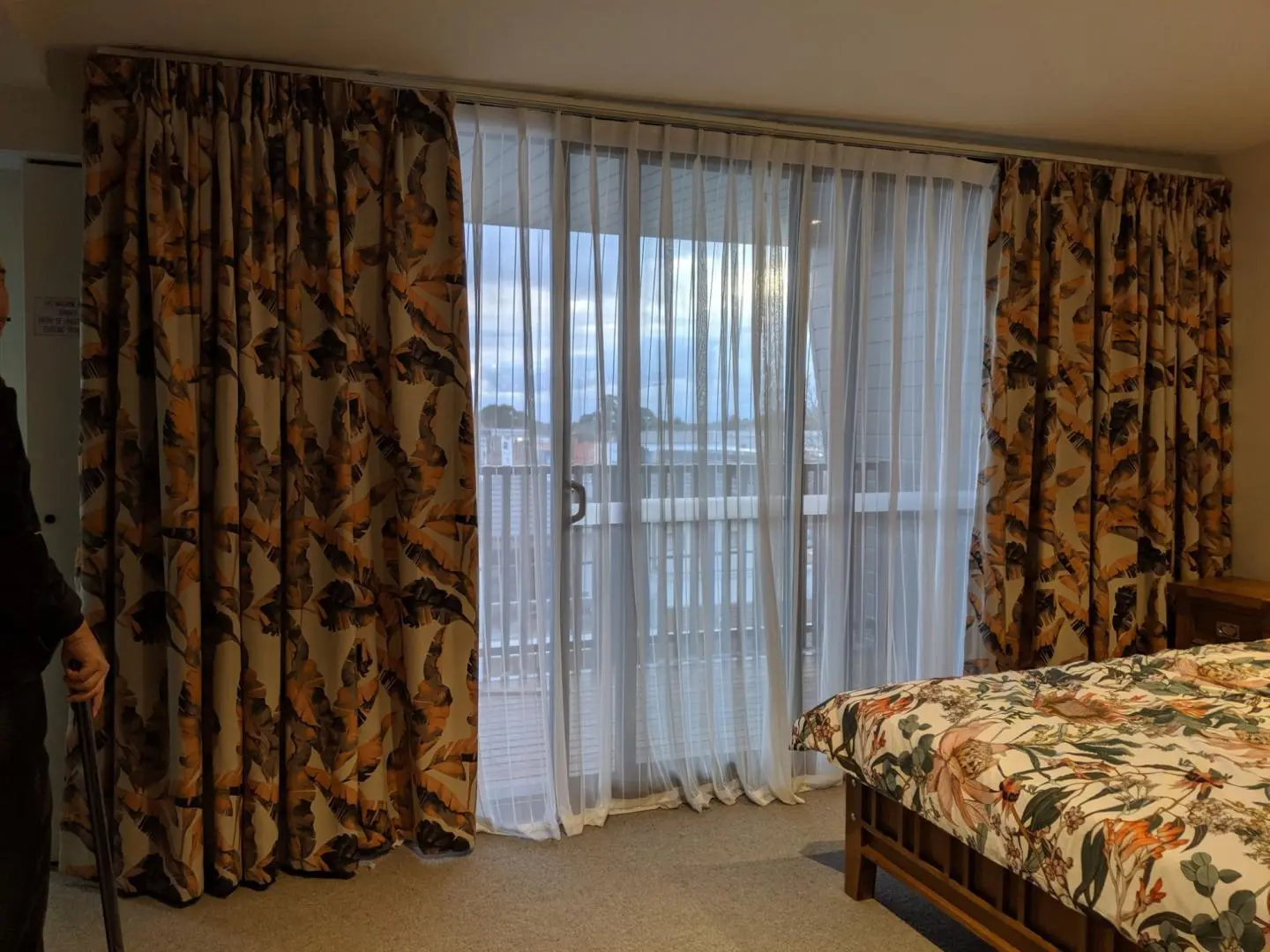 Cozy bedroom featuring floral curtains and a comfortable bed.