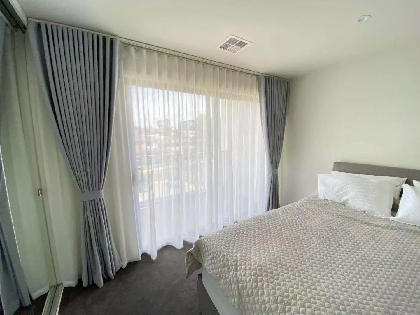 A bedroom features grey curtains for privacy and style.