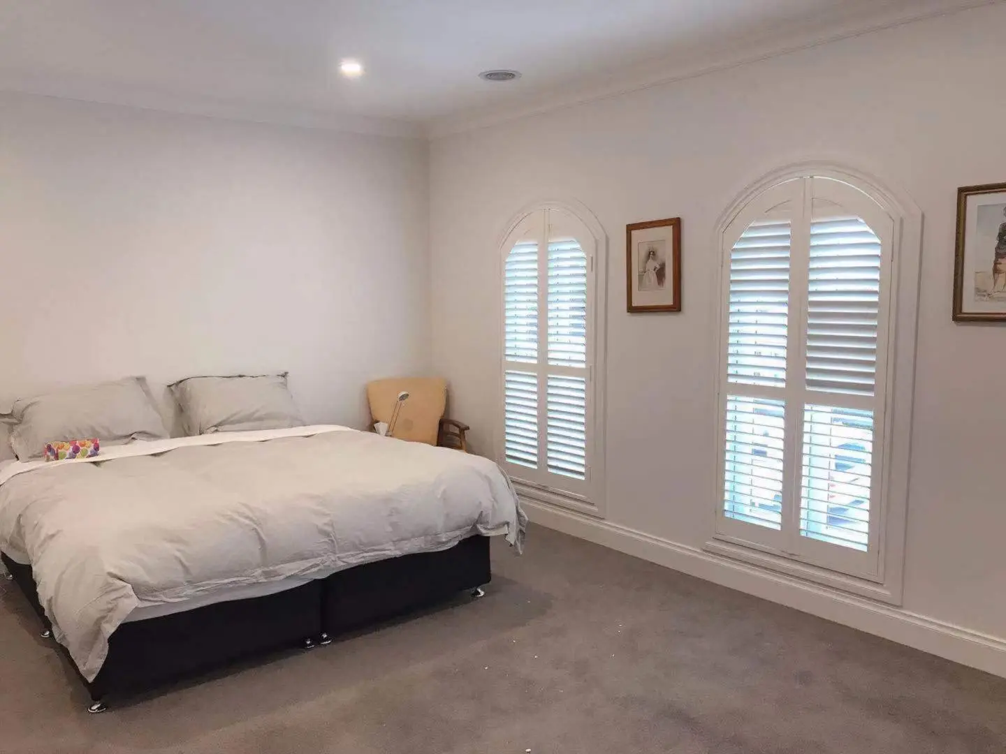 Cozy bedroom with arched windows, shutters, and a comfortable bed.