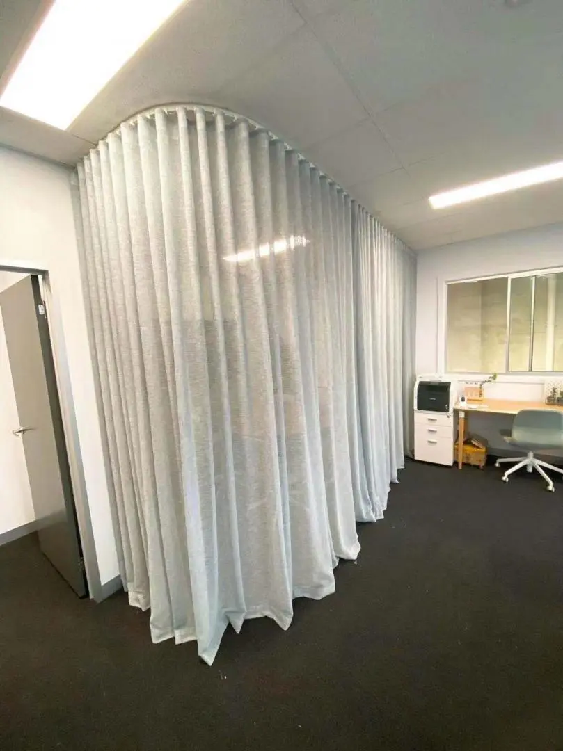 Office space design utilizes curved curtain dividers for privacy and style.