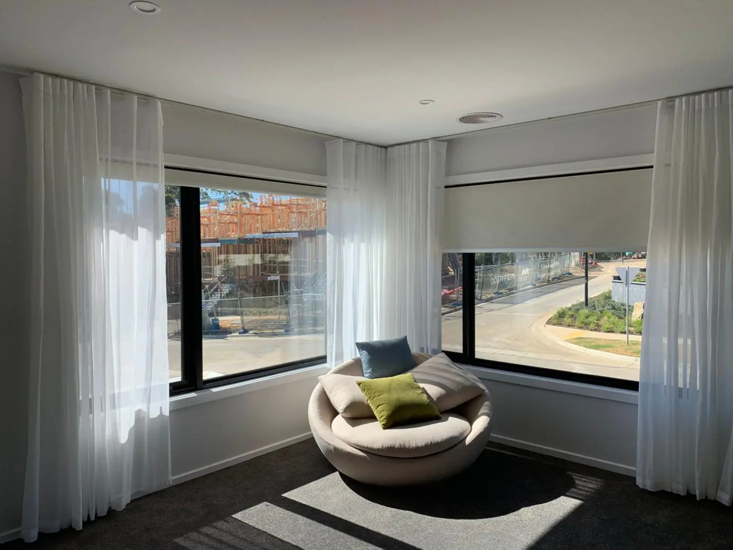 A cozy reading nook with sheer curtains and a round chair enjoys natural light.