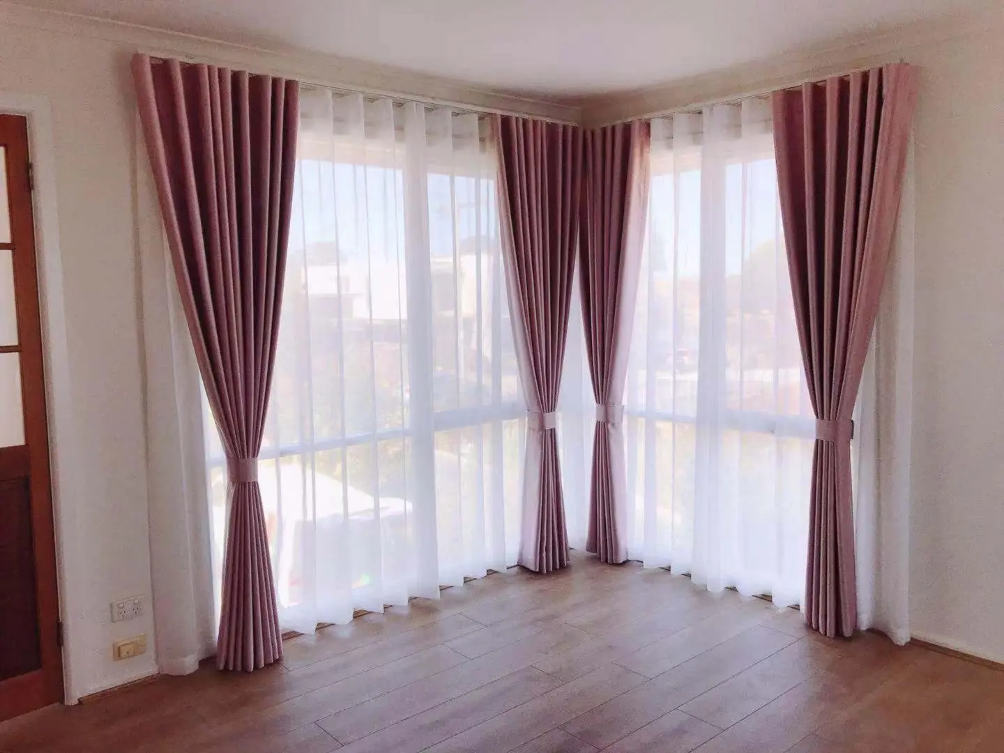 Pink curtains and sheer drapes beautifully frame a bright window.
