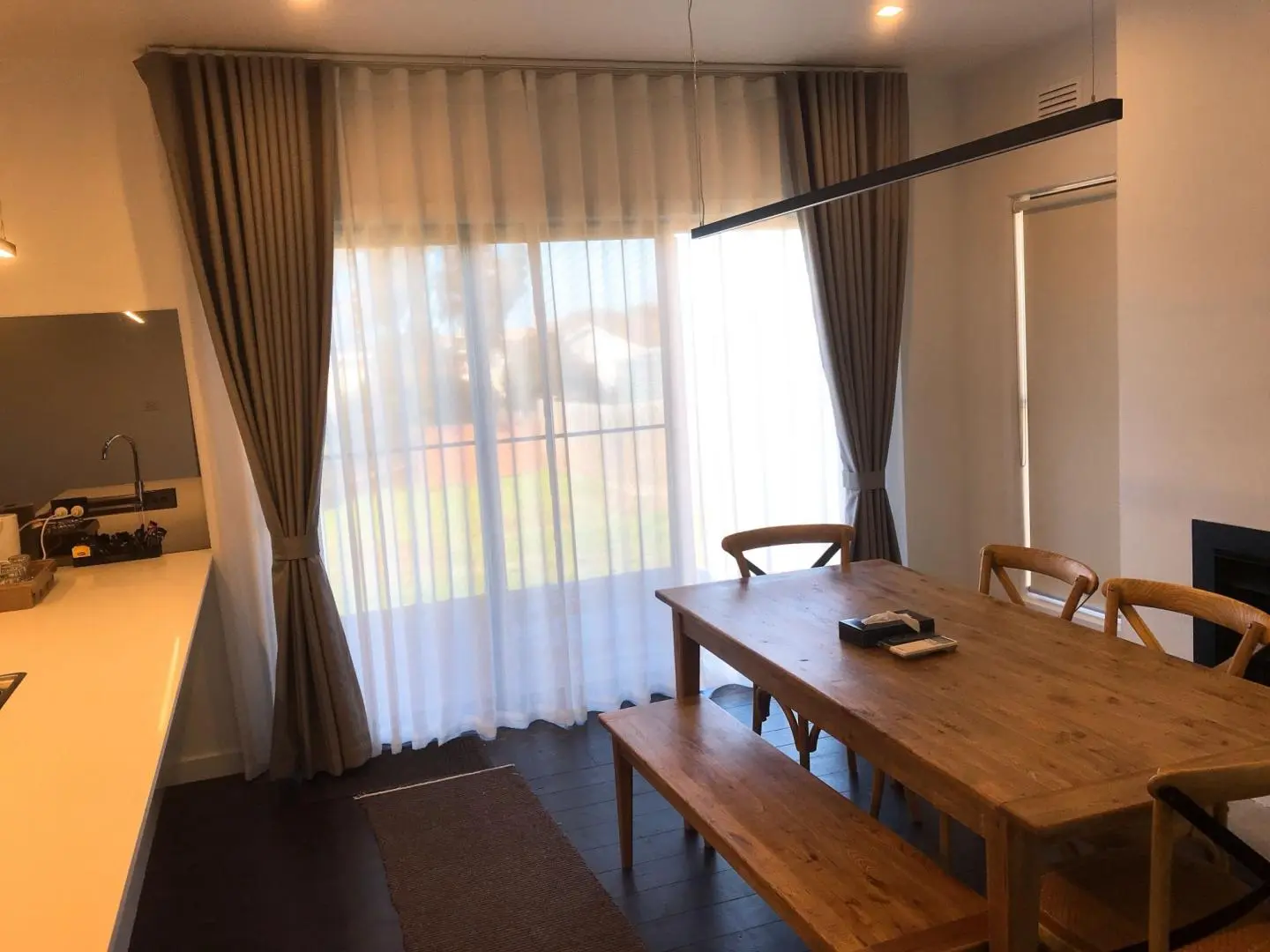 A dining room with a wooden table, chairs, and elegant curtains.