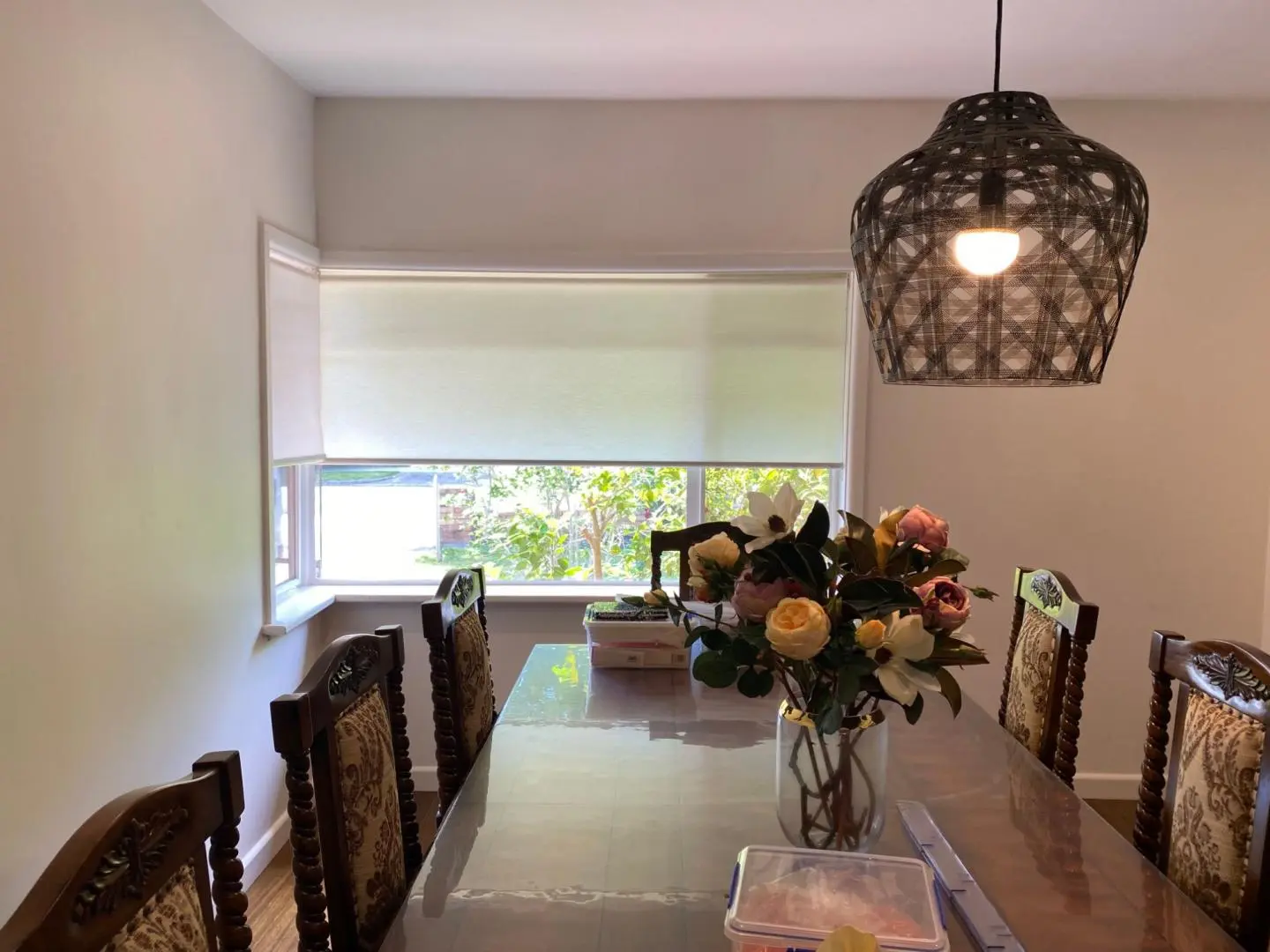 Bright dining room with roller blinds, a long table, and an eye-catching pendant lamp.