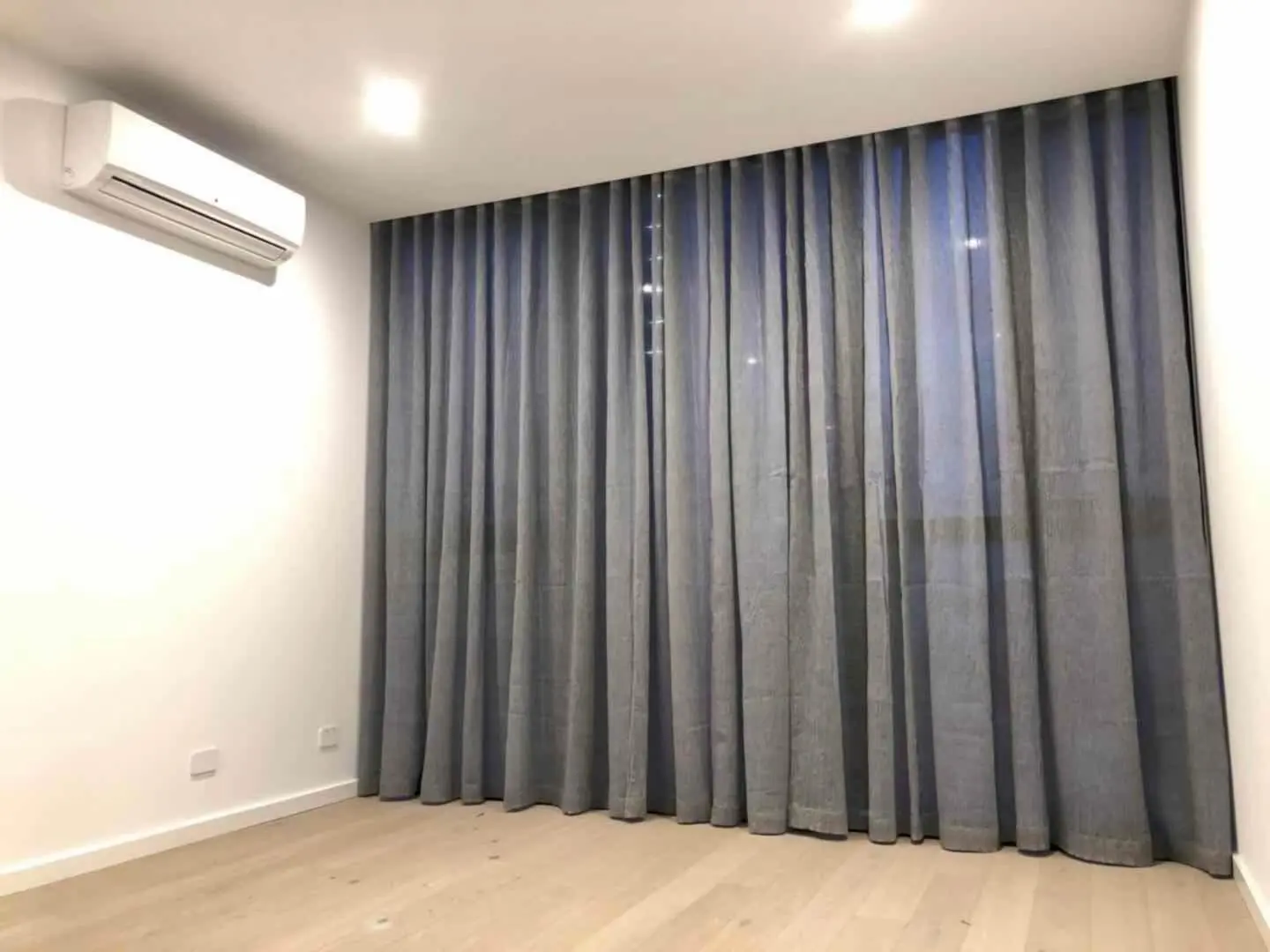Gray curtains adorn a modern room with wood flooring.