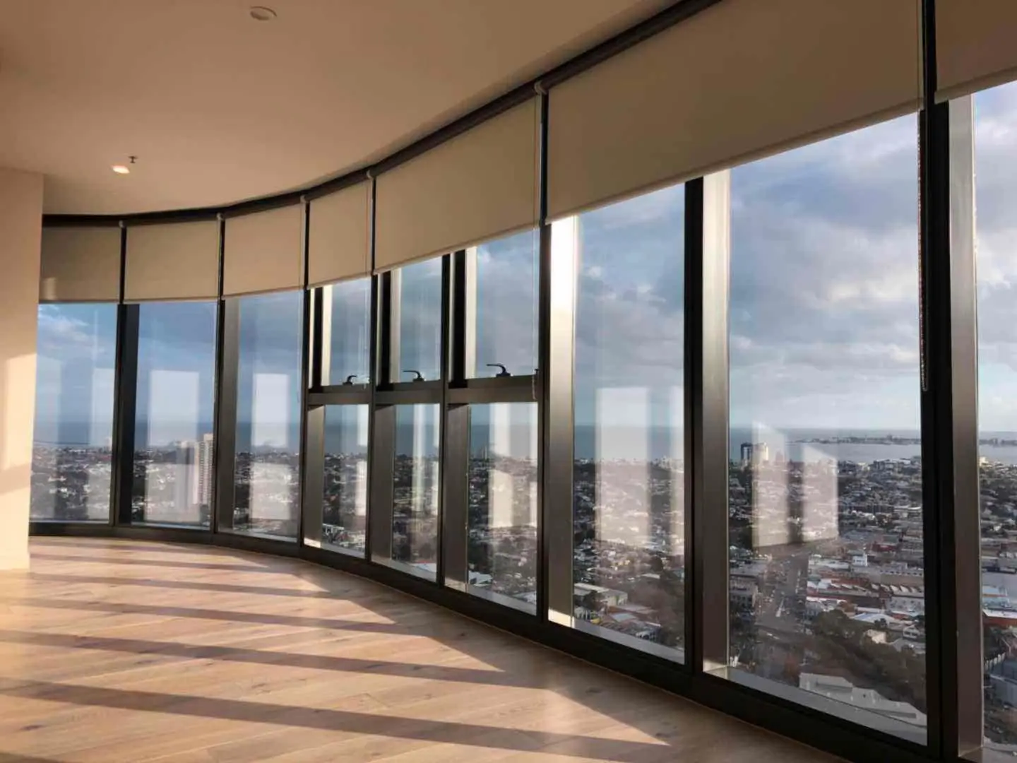 Roller shades on curved high-rise windows offer stunning city views.