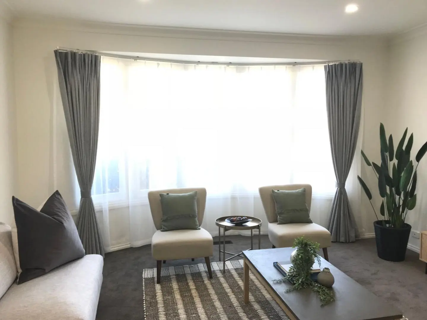 Bright living room with elegant gray curtains on a bay window, complemented by modern furniture.