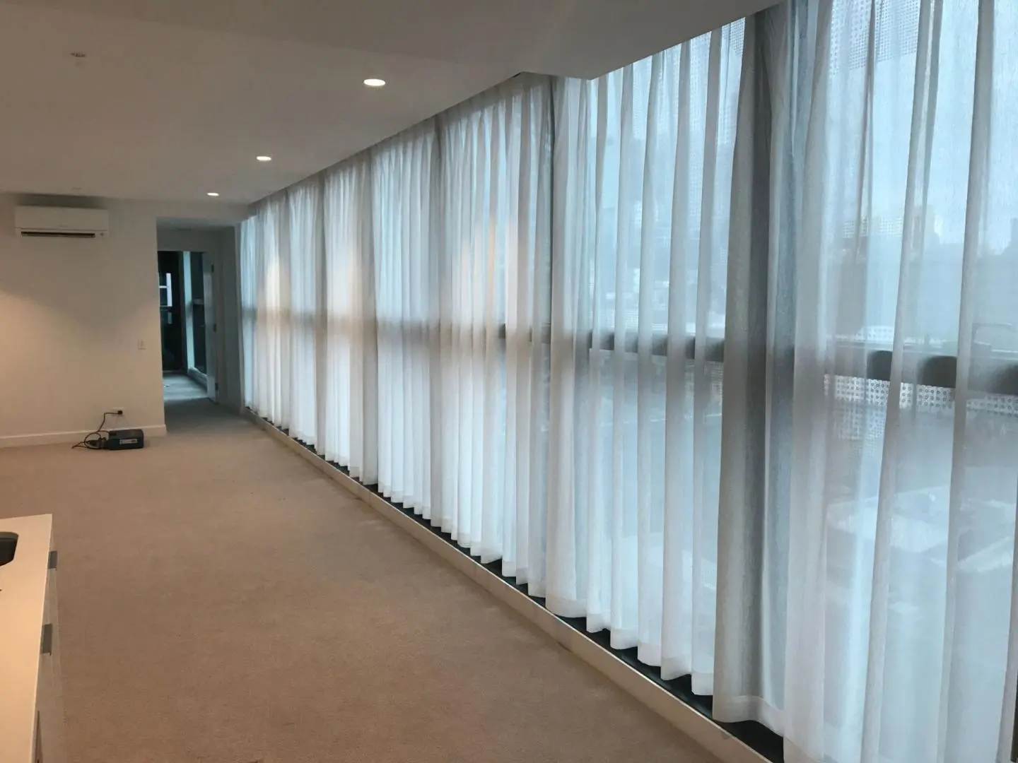 Sheer curtains in a modern living room offer privacy and soft sunlight filtering through large windows.
