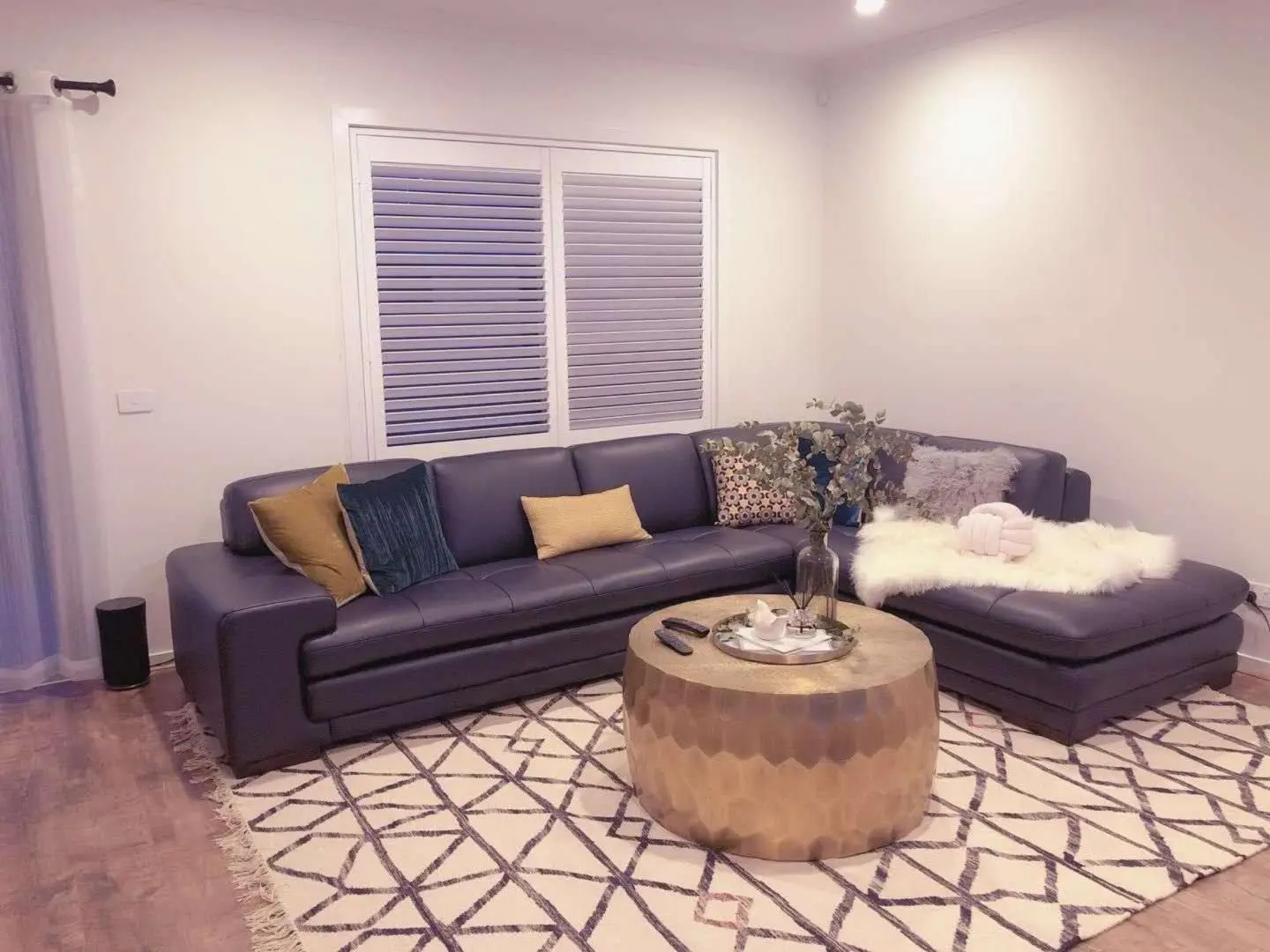 A modern living room showcases a stylish sectional sofa, a patterned rug, and natural light from a window.