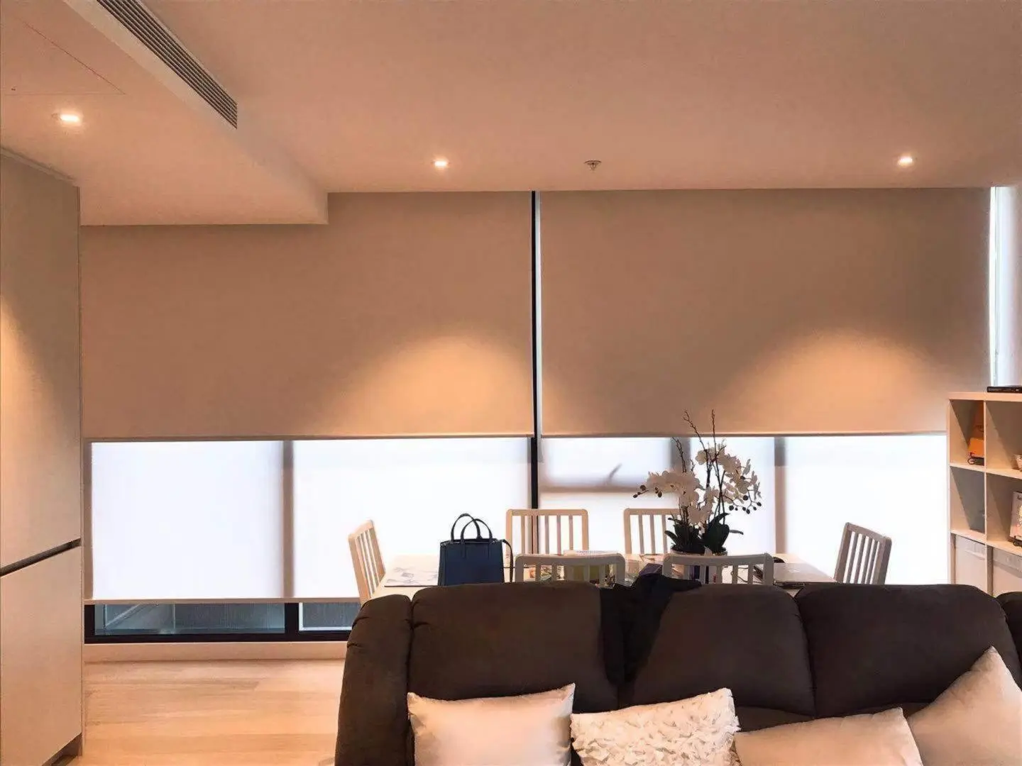 Beige roller blinds provide privacy and style in this modern living room and dining area.