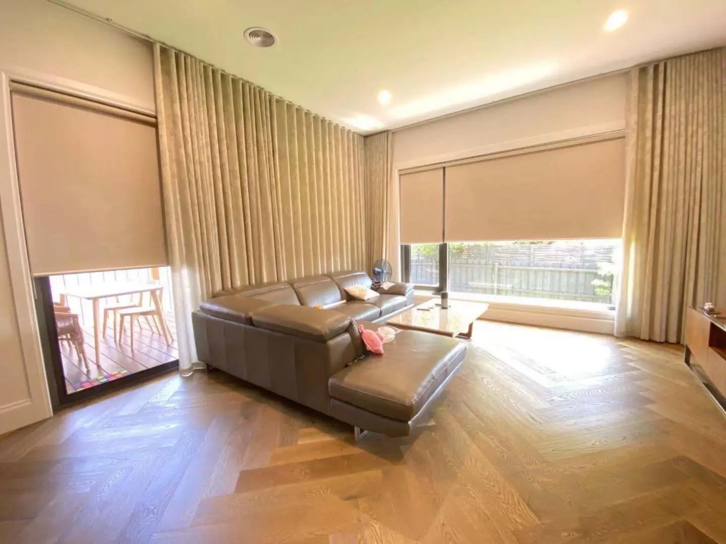 A modern living room with stylish window treatments and herringbone floors.