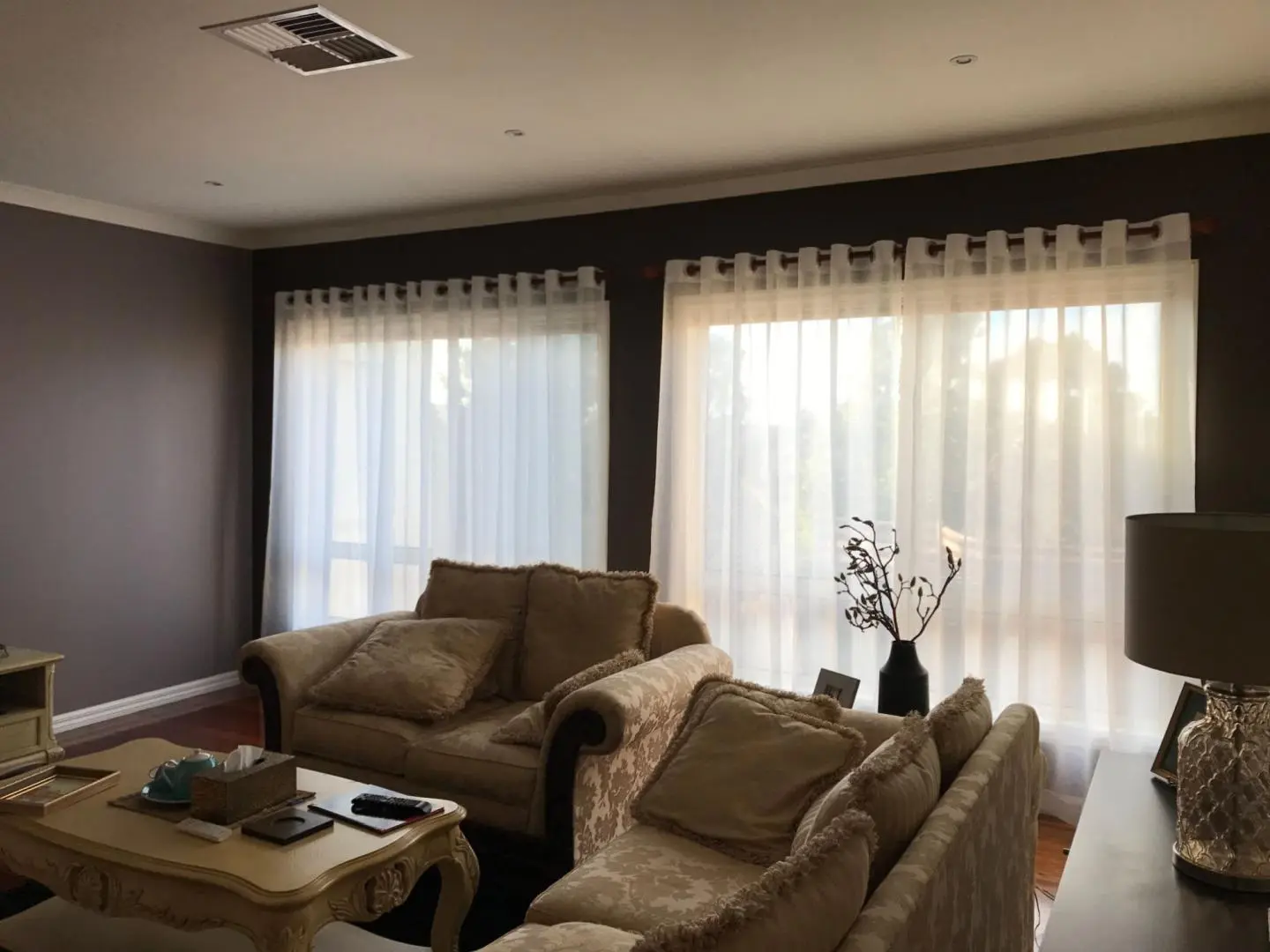Natural light brightens a cozy living room with beige sofas and sheer curtains.