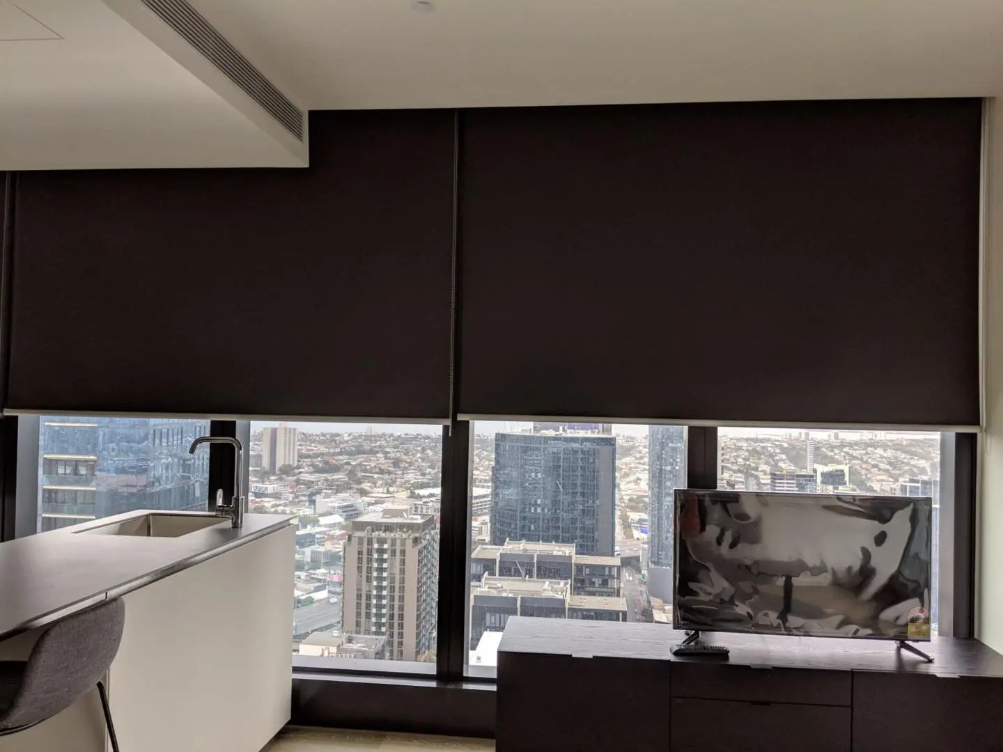 Blackout blinds provide light control and privacy in a modern city apartment with a view.