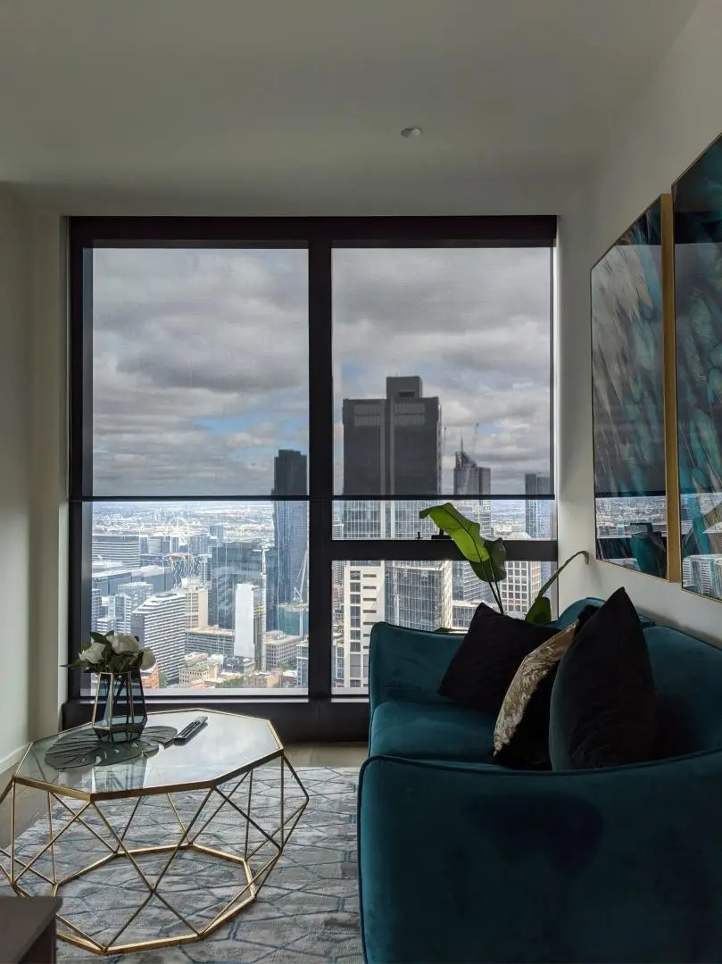 Modern living room overlooking a city skyline with window shades for light control.