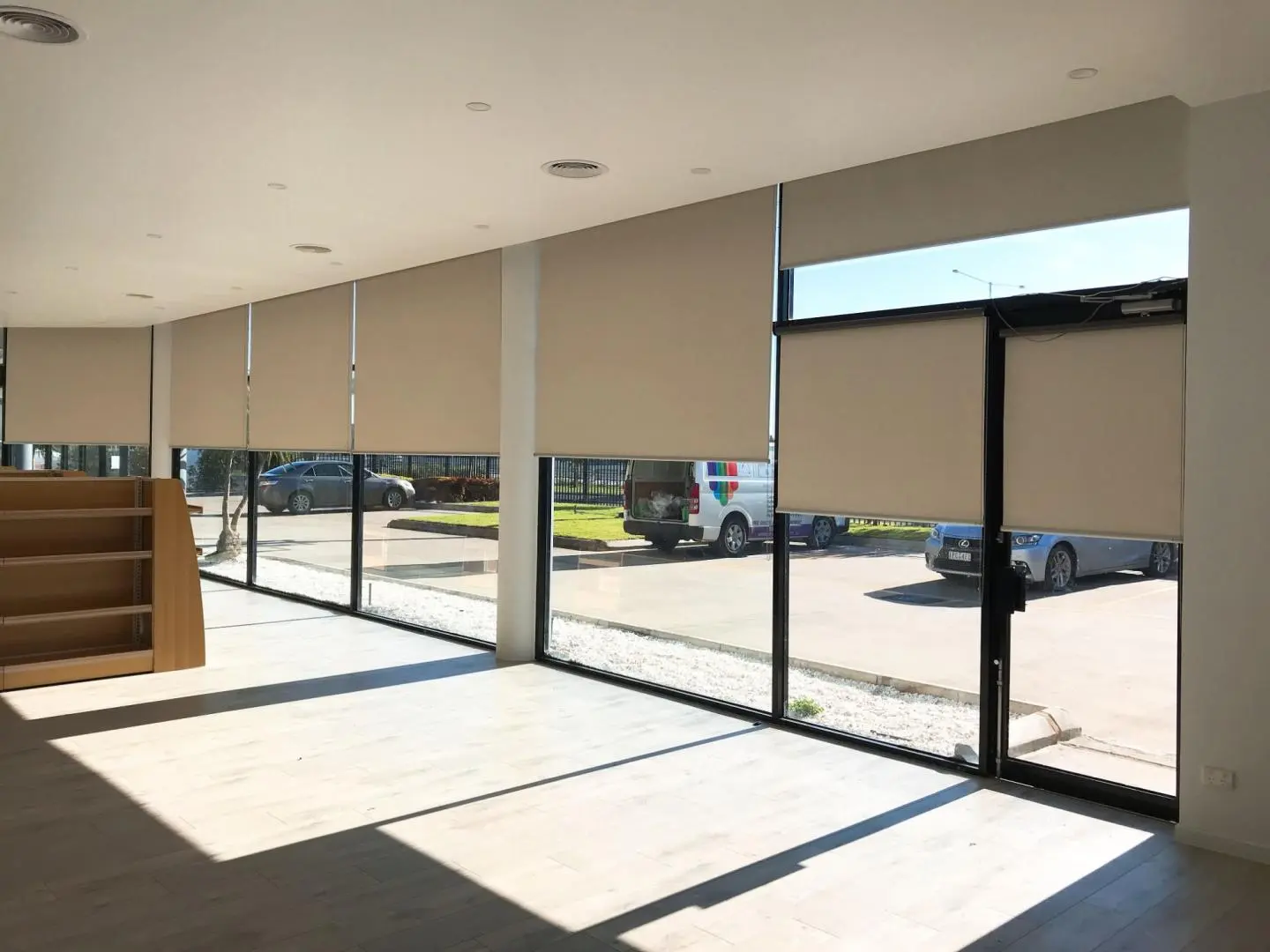 Spacious commercial interior with numerous large windows fitted with tan roller blinds to control natural light.