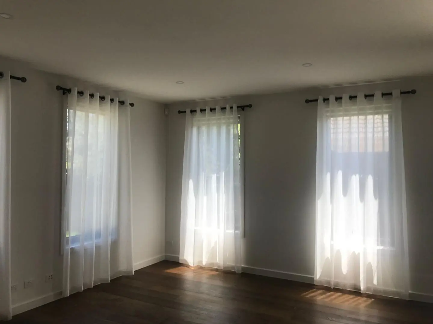 Sunlight streams through sheer white curtains in this bright, airy room.