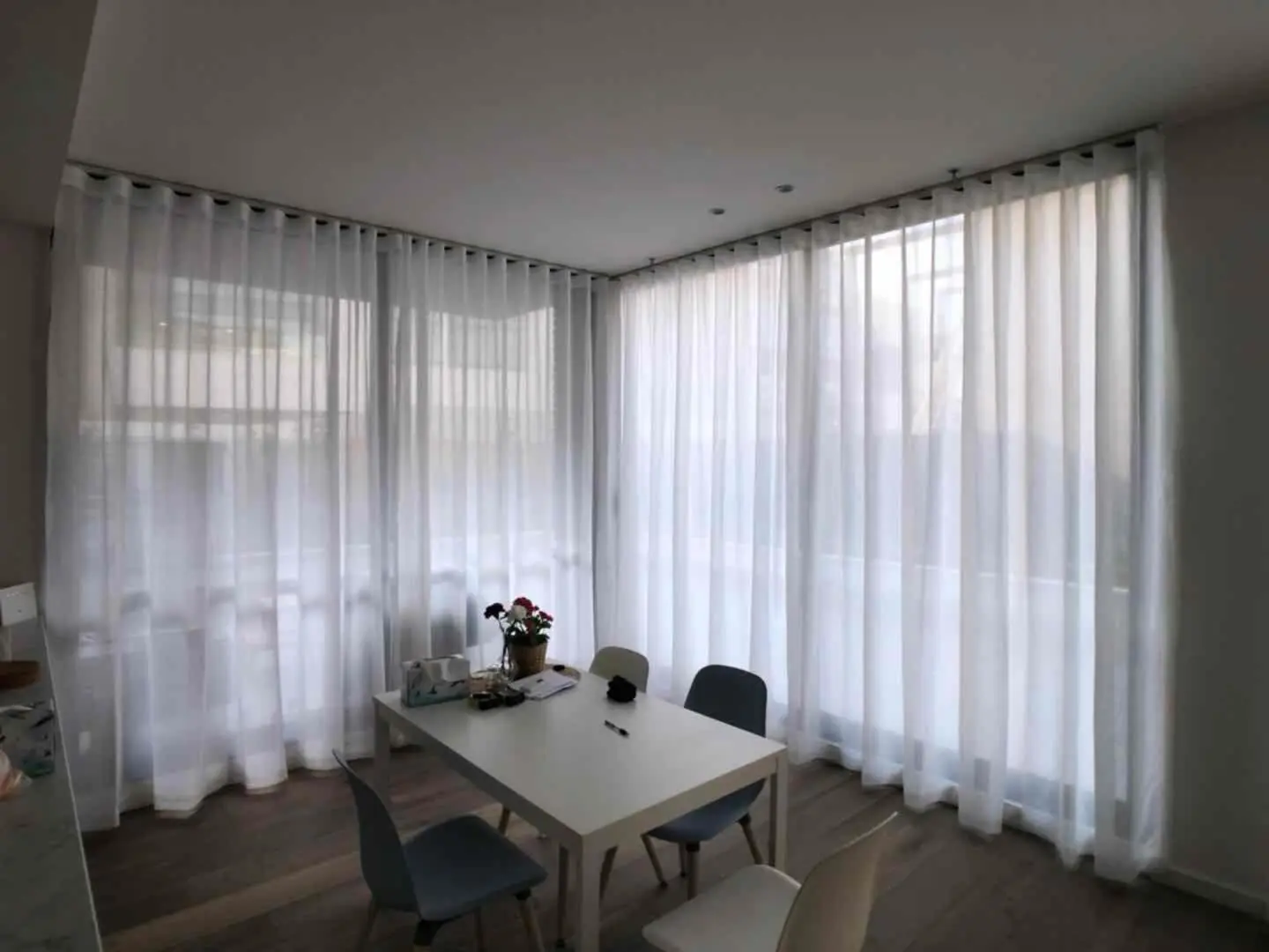 Sheer curtains grace a dining room, diffusing light and adding a touch of elegance.
