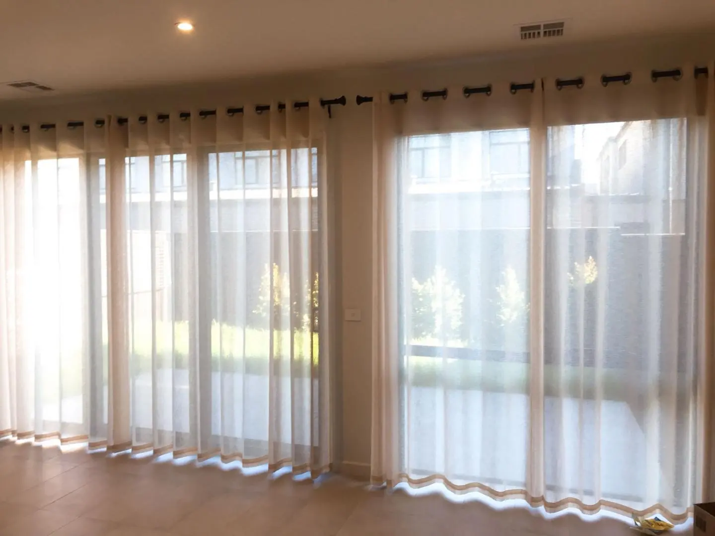 Elegant sheer grommet curtains adorn wide windows, softly filtering light and adding privacy.