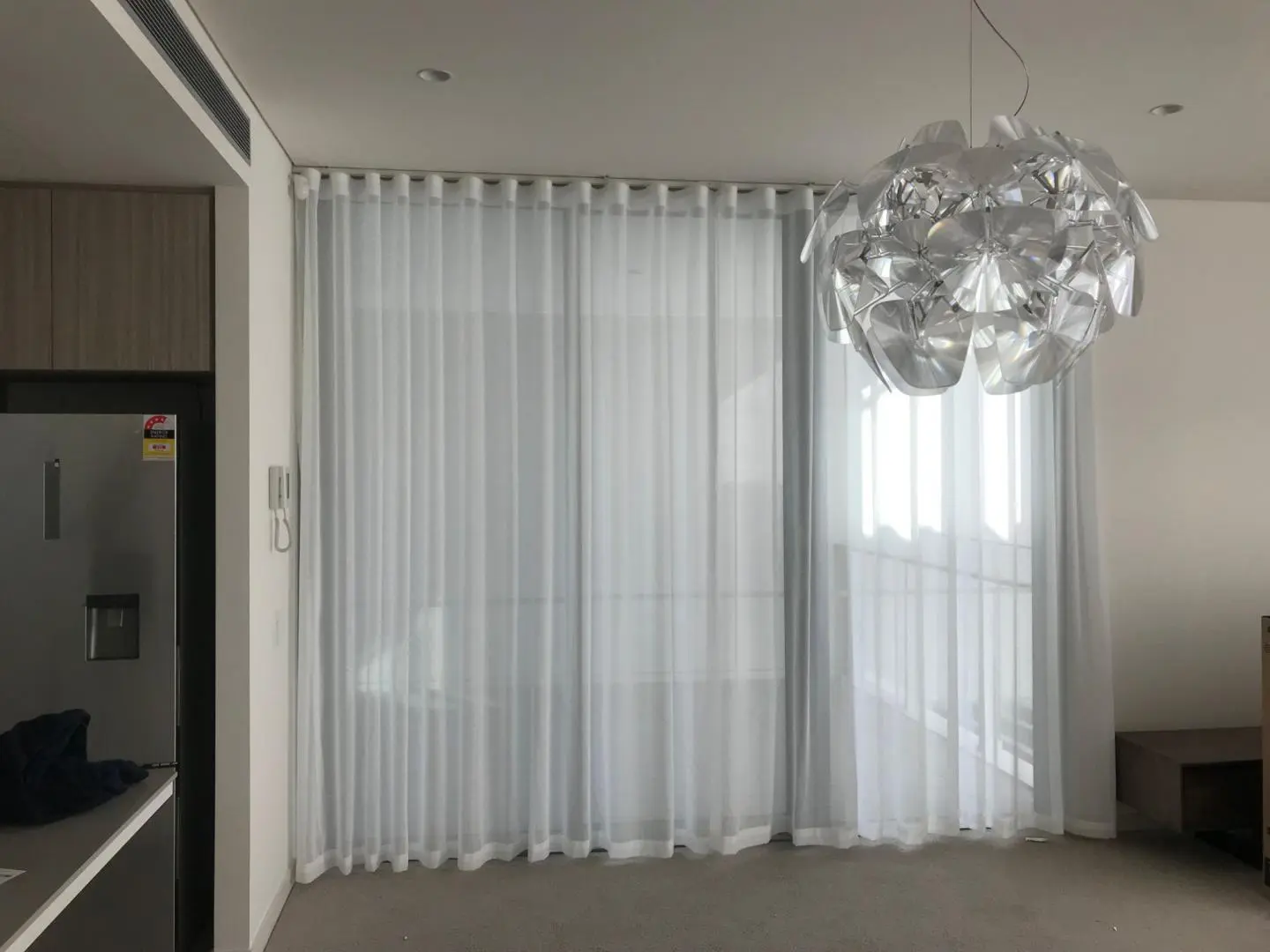 Living room with sheer white curtains and modern lighting.