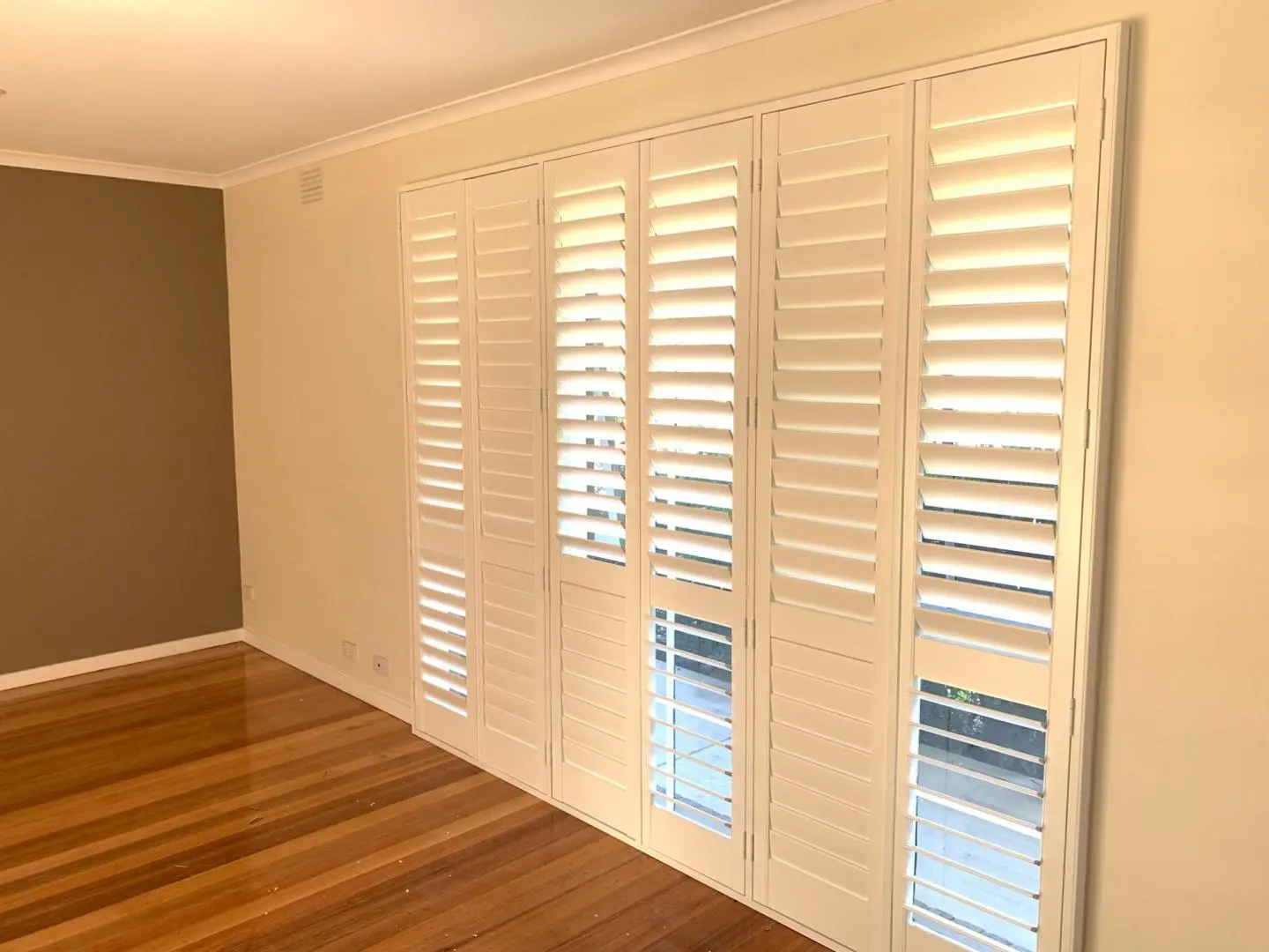 Interior design with white shutters in a living room, providing both aesthetic appeal and light control.