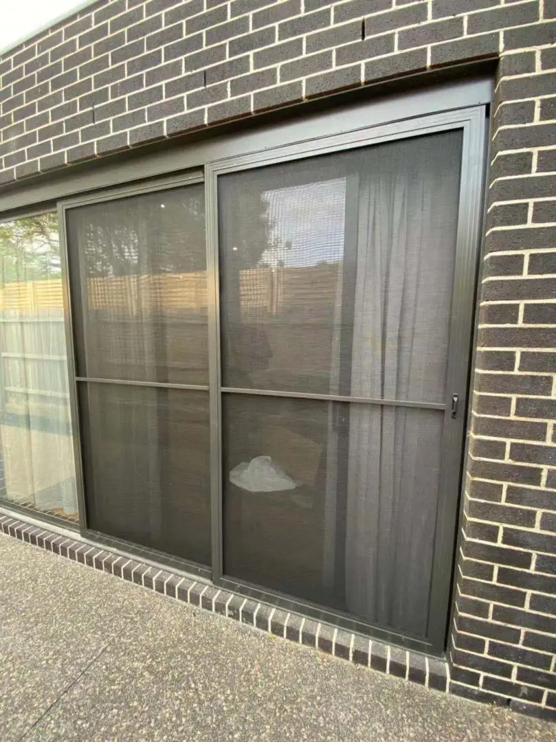 Sliding screen door on a brick exterior wall.